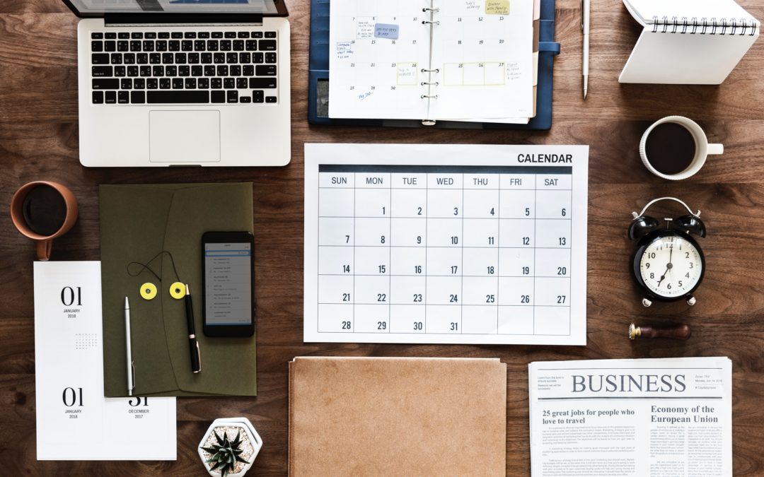 top view of a desk with items such as a laptop, calendar coffee mug, and tools all aligned perfectly in a grid